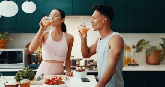 Male and female drinking smoothies and prepping healthy food in the kitchen