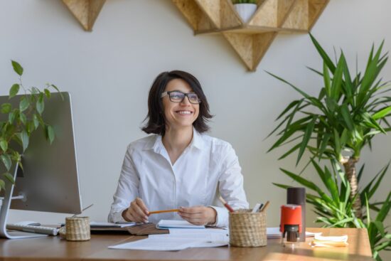 woman sitting at her home working desk smiling