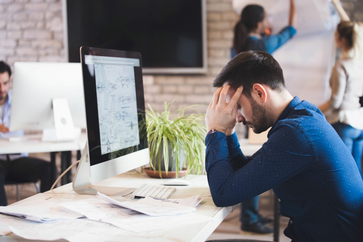 Man siting at work desk struggling to managing stress