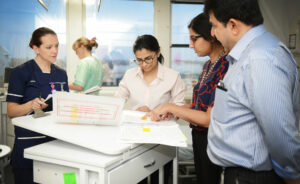 A group of healthcare staff from the Lancashire Teaching Hospitals Trust gather around a set of notes to discuss.