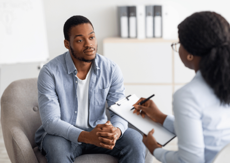 Female health worker taking notes whilst talking to concerned male