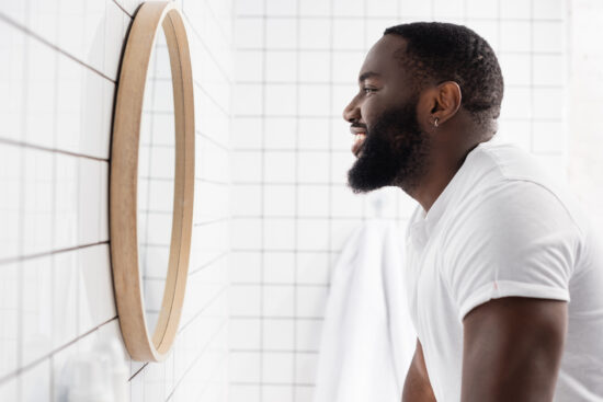 side view of afro-american man smiling and looking in mirror