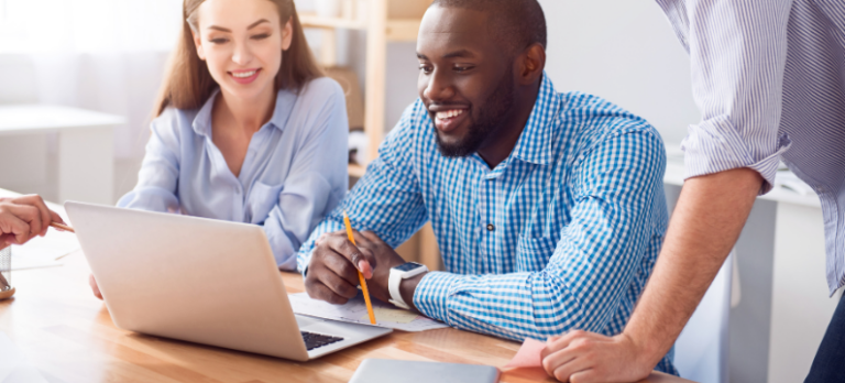 Group of employees smiling around a laptop