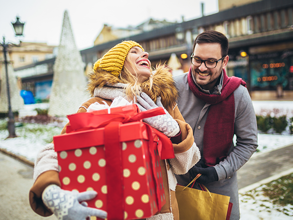 Happy couple christmas shopping carrying bags and large gift box