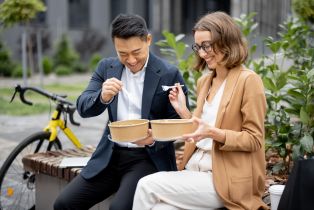 Man and woman outdoors eating lunch