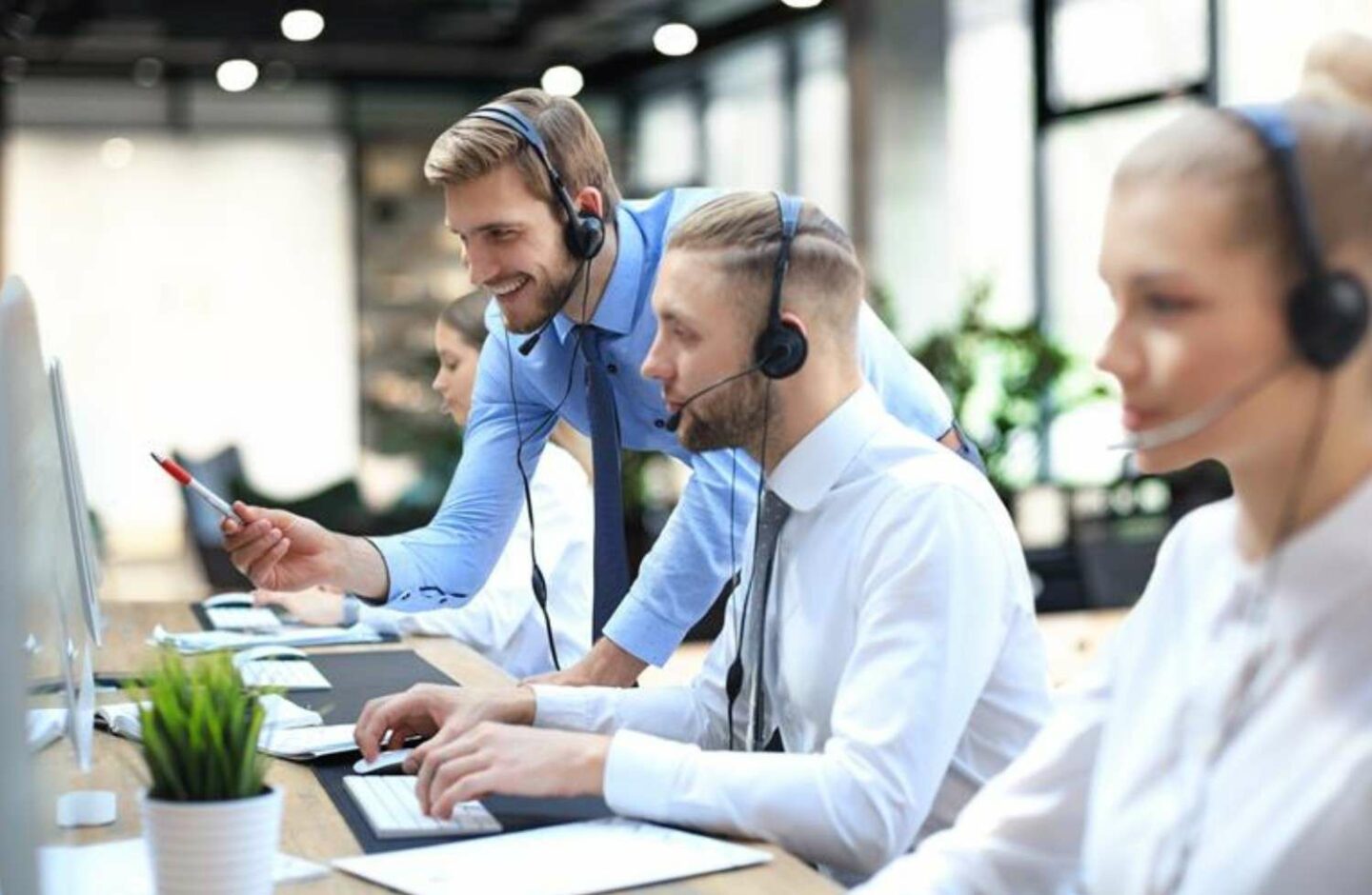 Employees facing computers with headsets on.