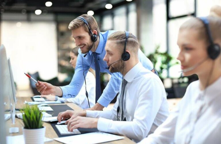 Employees facing computers with headsets on.