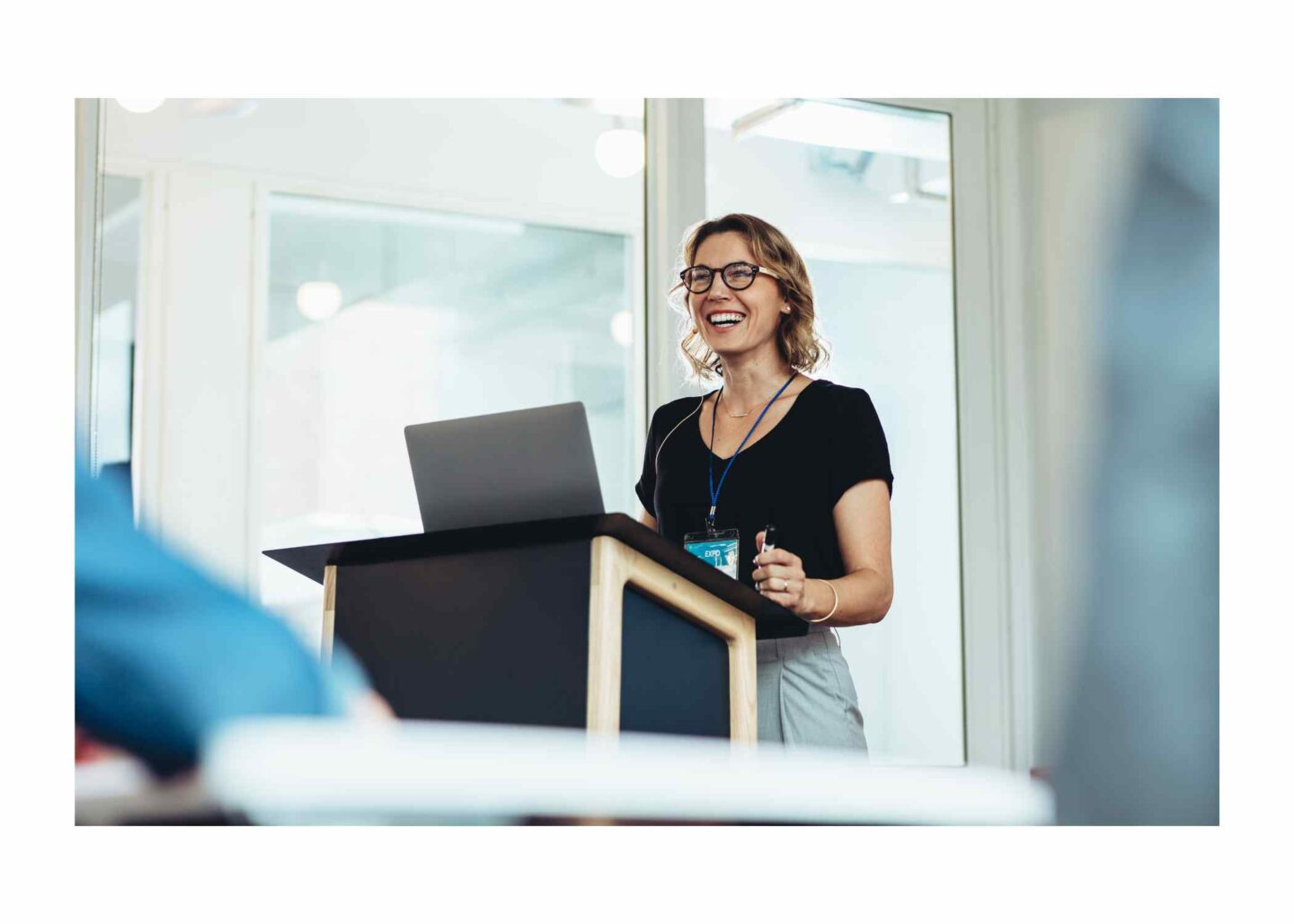Female speaker with glasses smiling on a podium