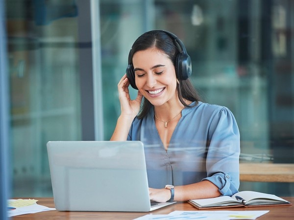 Female employee sat smiling in front of laptop with headset on