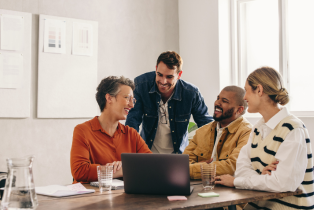 4 co workers collaborating around a laptop